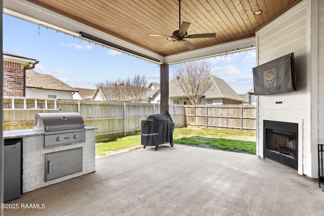 view of patio / terrace with grilling area, a large fireplace, a fenced backyard, and area for grilling