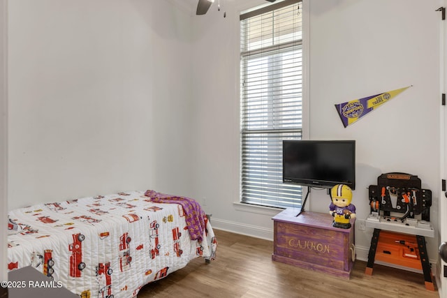 bedroom with baseboards, multiple windows, wood finished floors, and a ceiling fan