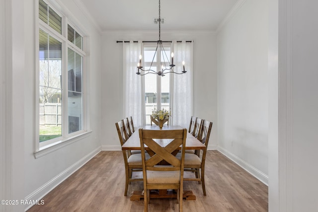 dining room with a notable chandelier, ornamental molding, baseboards, and wood finished floors