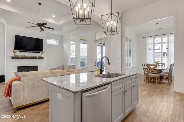 kitchen featuring a sink, dishwasher, ornamental molding, and a fireplace