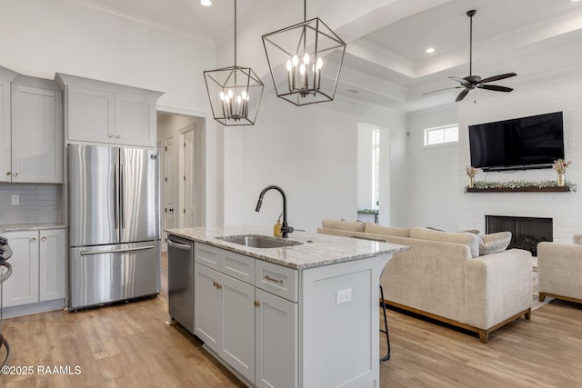 kitchen featuring a sink, ornamental molding, open floor plan, and stainless steel appliances