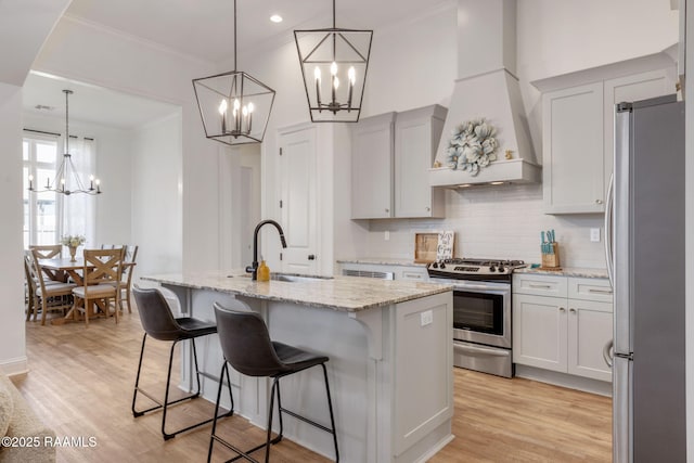 kitchen with a sink, tasteful backsplash, stainless steel appliances, light stone countertops, and custom exhaust hood