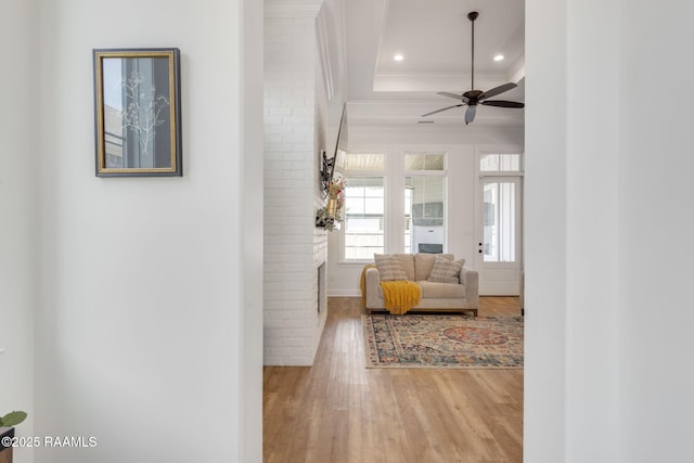 interior space with light wood finished floors, recessed lighting, a tray ceiling, and ornamental molding