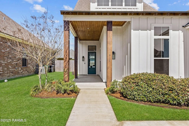 property entrance featuring board and batten siding, a shingled roof, and a yard