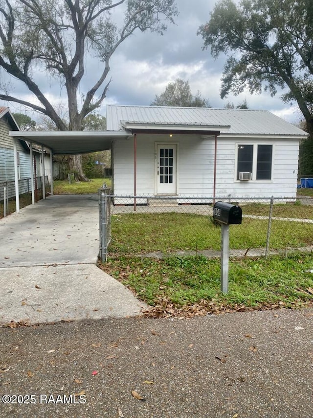 view of front of home featuring concrete driveway, a front yard, metal roof, fence, and an attached carport