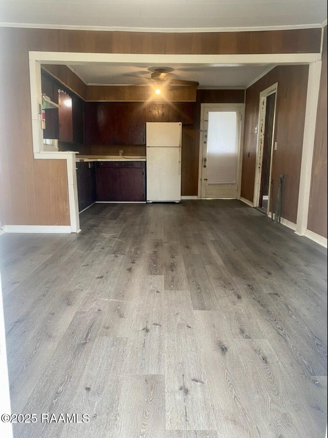 garage featuring wood walls, freestanding refrigerator, and baseboards