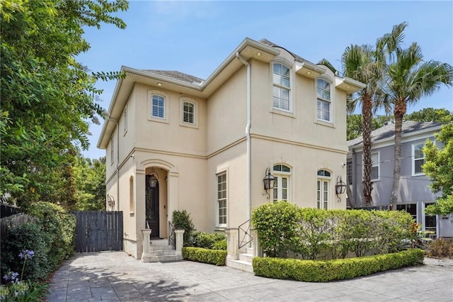 mediterranean / spanish-style home with fence and stucco siding