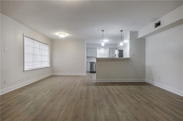 unfurnished living room with dark wood-type flooring and baseboards