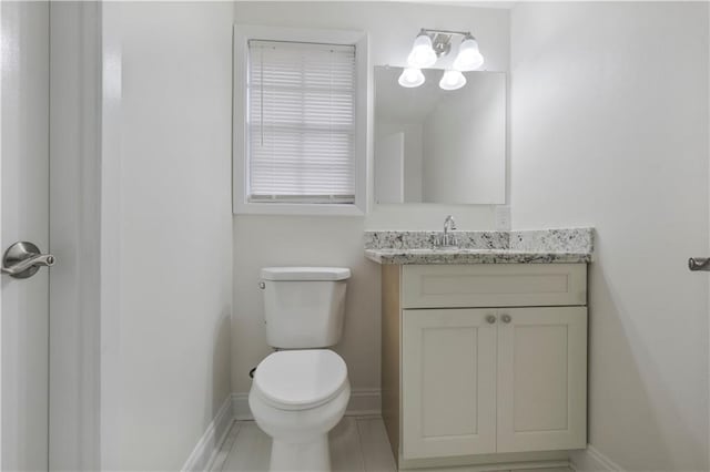 bathroom with baseboards, vanity, and toilet