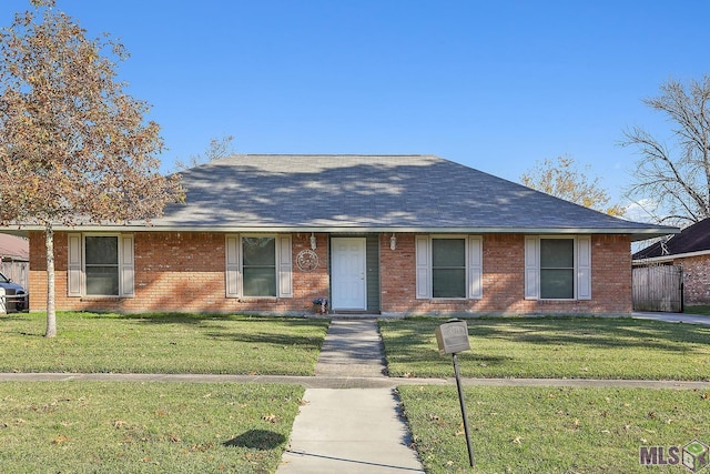 ranch-style home with brick siding, a shingled roof, and a front yard