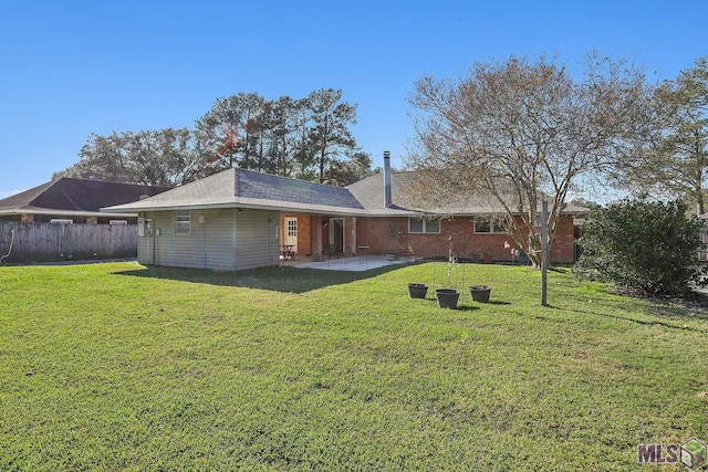 rear view of property with brick siding, a lawn, a patio area, and fence