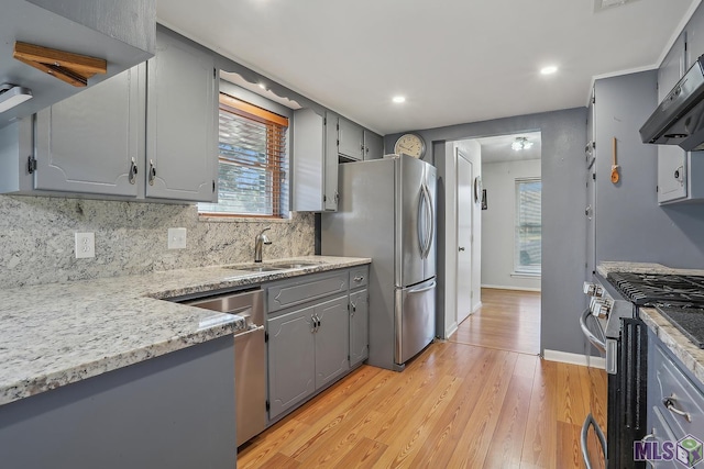 kitchen featuring under cabinet range hood, stainless steel appliances, a sink, and gray cabinetry