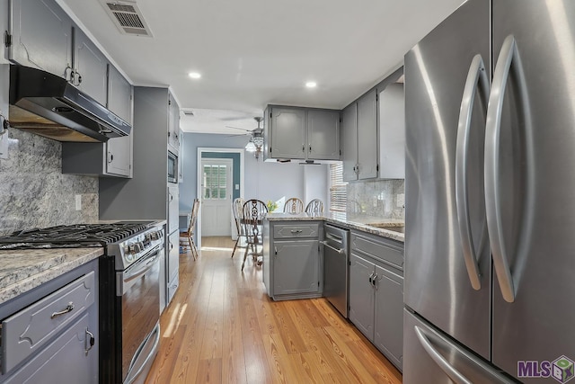 kitchen with visible vents, appliances with stainless steel finishes, a peninsula, gray cabinets, and under cabinet range hood