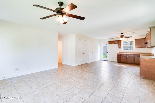 interior space featuring ceiling fan, baseboards, a sink, and light tile patterned flooring