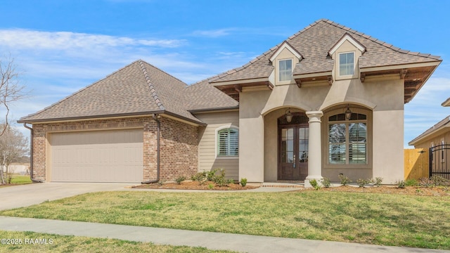 french provincial home featuring a garage, brick siding, driveway, french doors, and a front lawn