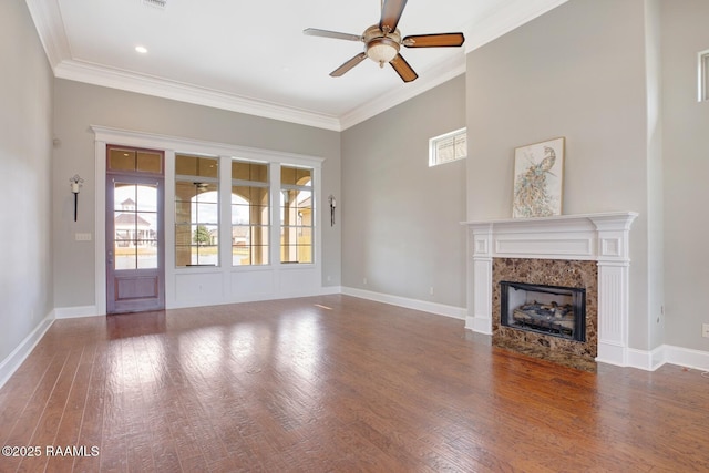 unfurnished living room featuring crown molding, a fireplace, baseboards, and wood finished floors