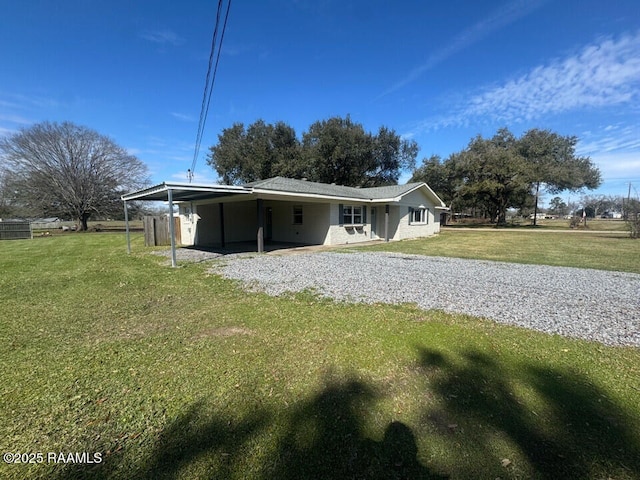 back of property with a yard, an attached carport, and driveway