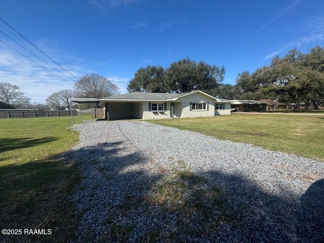 view of front of house with driveway, an attached carport, a front yard, and fence