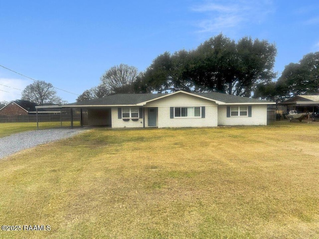 single story home featuring gravel driveway, fence, a front yard, a carport, and brick siding