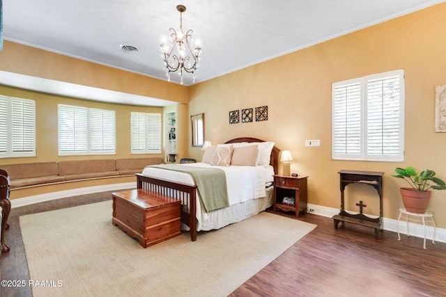 bedroom with an inviting chandelier, baseboards, wood finished floors, visible vents, and ornamental molding