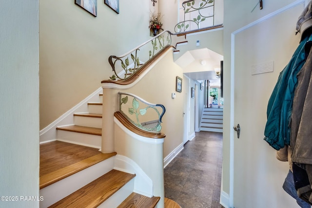 stairway featuring a high ceiling and baseboards