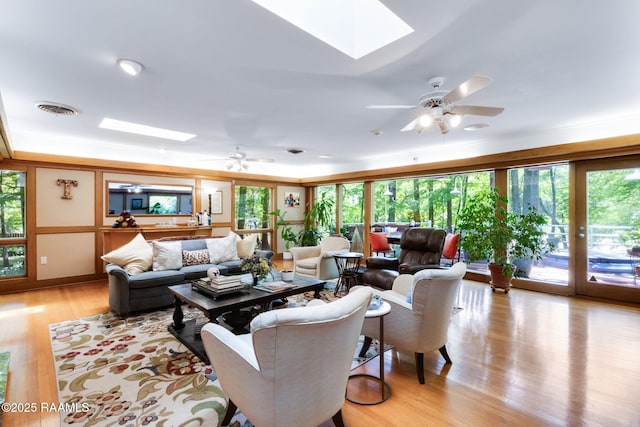 living room featuring visible vents, a ceiling fan, light wood-style floors, and a skylight