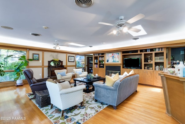 living area with visible vents, a ceiling fan, and a skylight