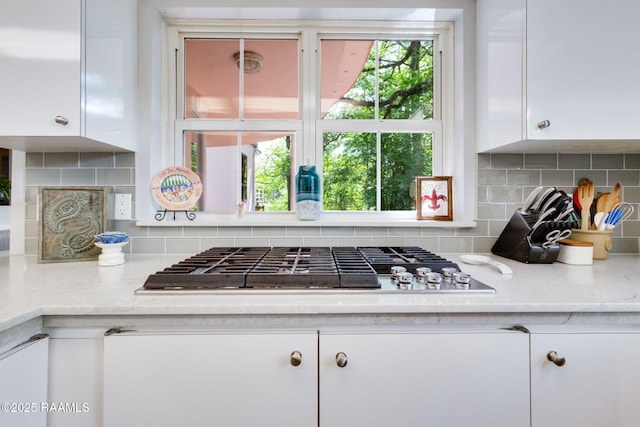 kitchen featuring white cabinets, stainless steel gas cooktop, and backsplash