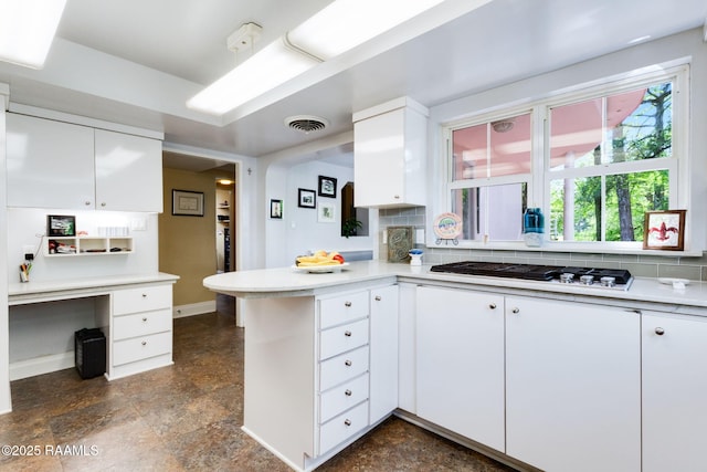 kitchen with white cabinets, a peninsula, and white gas stovetop