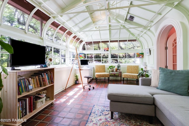 sunroom with visible vents, baseboards, tile patterned flooring, and high vaulted ceiling