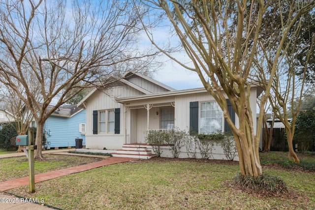 bungalow-style home with a porch, fence, a front lawn, and brick siding