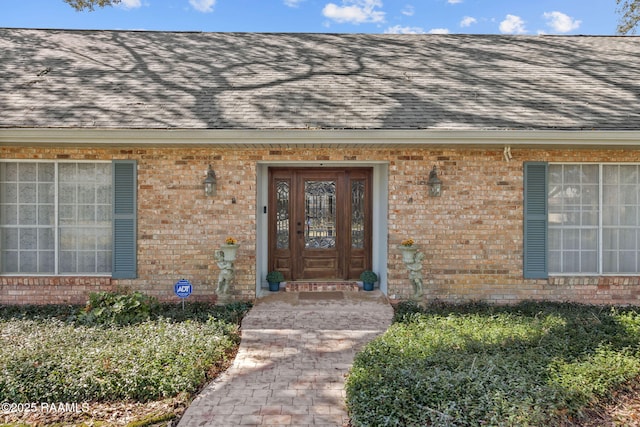 property entrance with roof with shingles and brick siding