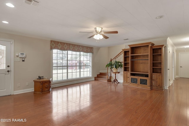 unfurnished living room featuring baseboards, visible vents, stairway, ornamental molding, and wood finished floors