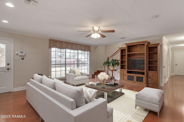 living room featuring visible vents, crown molding, baseboards, and wood finished floors