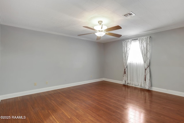 spare room with ceiling fan, wood finished floors, visible vents, baseboards, and crown molding