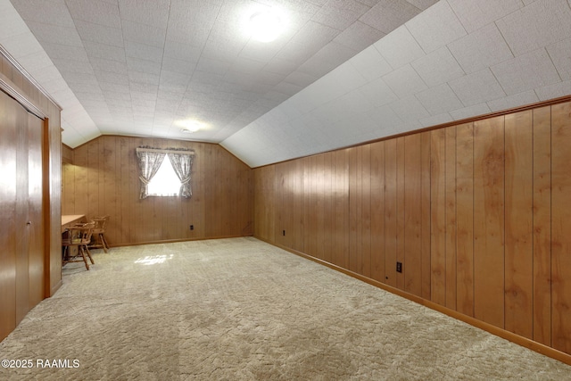 bonus room with wooden walls, baseboards, vaulted ceiling, and carpet flooring