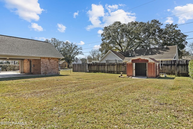 view of yard featuring an outbuilding, a fenced backyard, and a storage unit