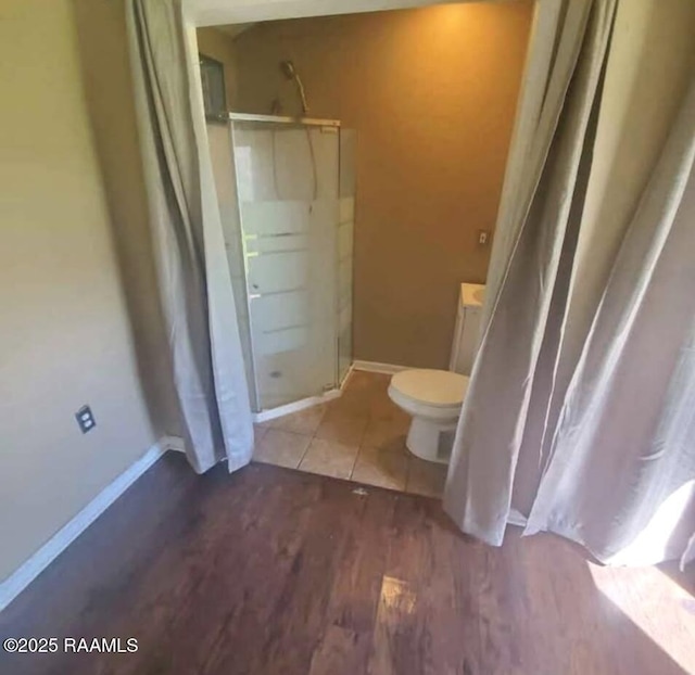 full bath featuring a walk in shower, toilet, baseboards, and wood finished floors