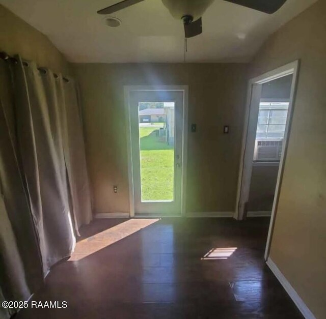 doorway featuring cooling unit, baseboards, plenty of natural light, and wood finished floors