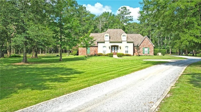 french country home featuring driveway and a front lawn