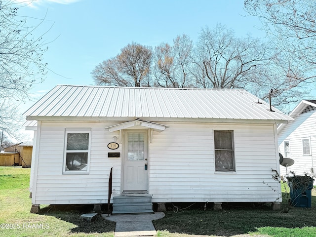 bungalow with entry steps, metal roof, and a front lawn