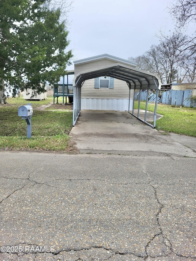 view of car parking with driveway, fence, and a detached carport