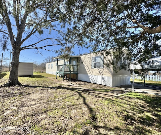 view of home's exterior featuring driveway, a yard, a carport, and an outbuilding