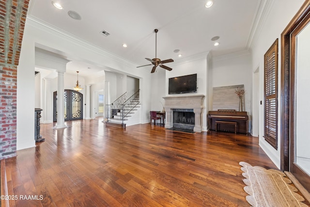 unfurnished living room featuring stairway, visible vents, ornate columns, a fireplace with flush hearth, and wood-type flooring