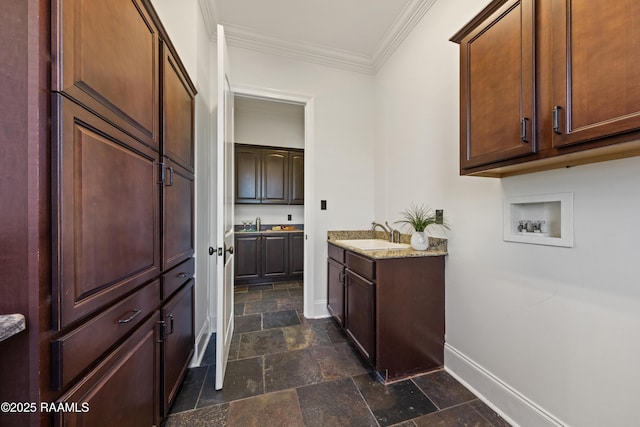 bathroom with stone tile floors, vanity, crown molding, and baseboards