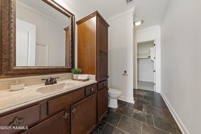 bathroom featuring toilet, stone tile flooring, vanity, and ornamental molding