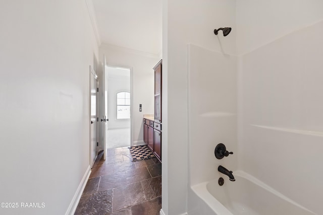 full bath featuring shower / washtub combination, stone tile flooring, crown molding, baseboards, and vanity