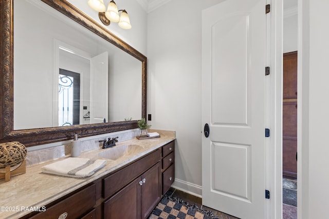 bathroom with baseboards, ornamental molding, and vanity