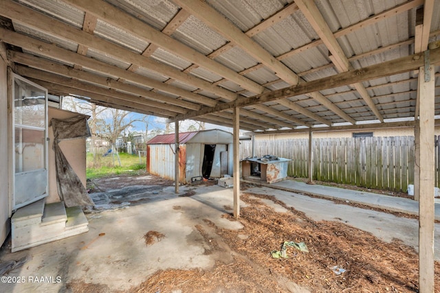 view of patio with a shed, fence, and an outdoor structure