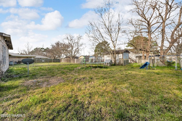 view of yard featuring a trampoline, a playground, and a fenced backyard